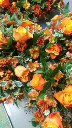 Orange table centrepieces, roses, crysanthemums and greenery